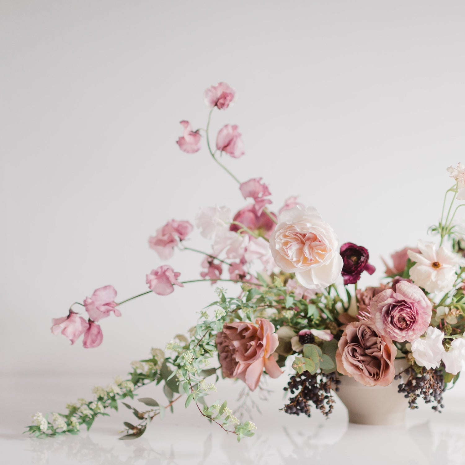 Stunning floral arrangement including roses, sweet peas, ranunculus, spirea and berries